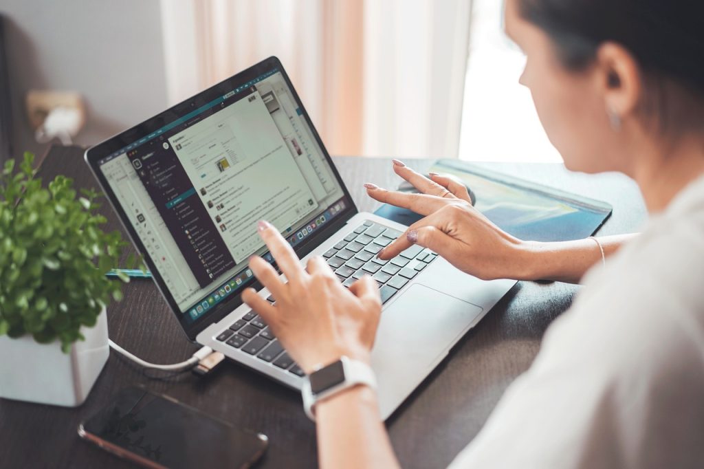 A woman in a home office looking at her laptop screen.