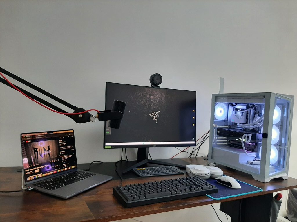 Photo of Marko's home desk with the AMD desktop visible and the
travel kit packed in a backpack beside it. Alt text: "Home desktop with
travel kit packed beside it - split setup for remote work.