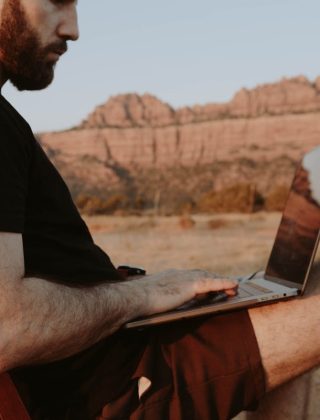 Remote worker using laptop outdoors in Sedona desert landscape with red rock formations — working from anywhere as a digital nomad in 2026