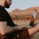 Remote worker using laptop outdoors in Sedona desert landscape with red rock formations — working from anywhere as a digital nomad in 2026