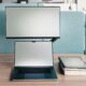 Laptop with second monitor stacked above on adjustable arm in coworking space - second screen setup for remote work productivity