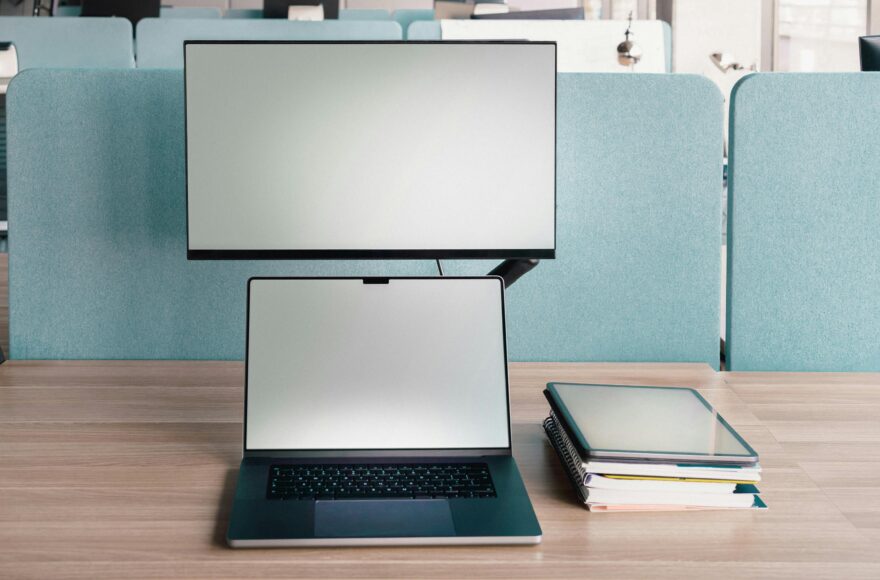 Laptop with second monitor stacked above on adjustable arm in coworking space - second screen setup for remote work productivity